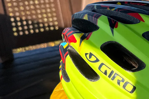 Close owner photo of the larger visored bright-green Giro Hale MIPS against a shaded metal shelter