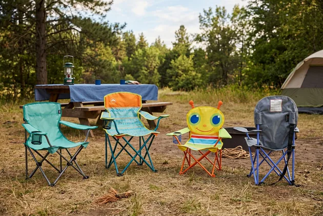 Four kids camping chairs arranged on level ground at a wooded campsite