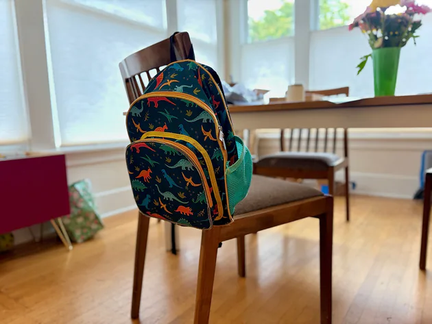 Our Wildkin Jurassic Dinosaurs 12-inch backpack hanging on a dining chair