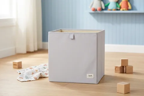 Light gray 3 Sprouts fabric storage cube on a wooden playroom floor beside wooden blocks