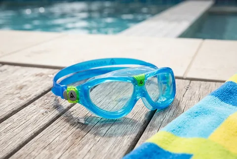 Wide soft-seal kids swim goggles on a poolside towel