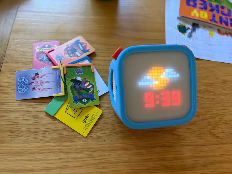 Our Yoto Player 3rd Generation in its blue Adventure Jacket beside cards on a keychain