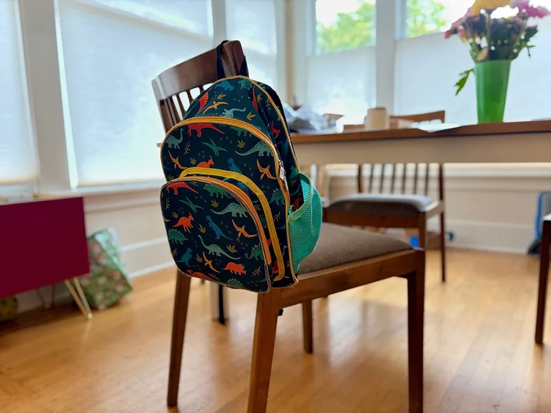 Our Wildkin Jurassic Dinosaurs 12-inch backpack hanging on a dining chair