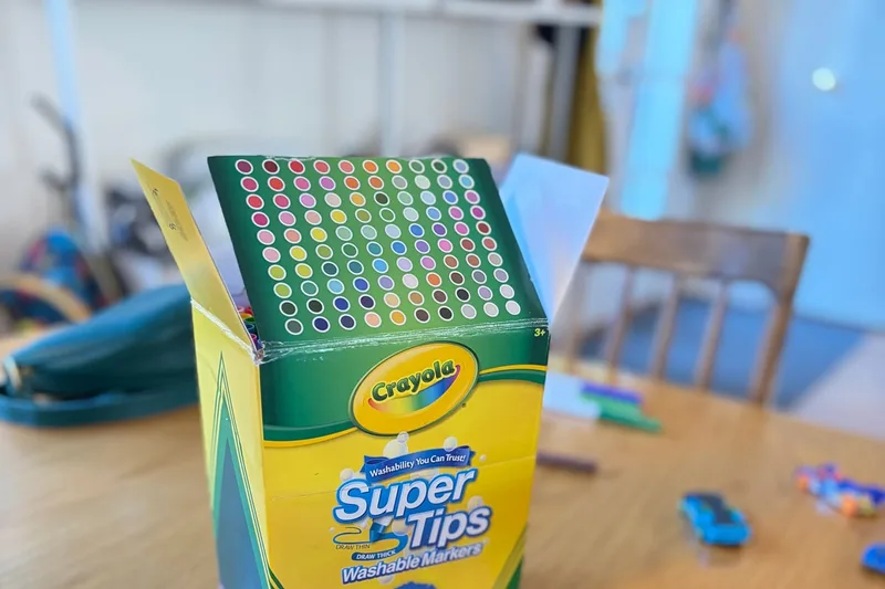 Owner-used Crayola Super Tips 100-count marker box open on a family art table