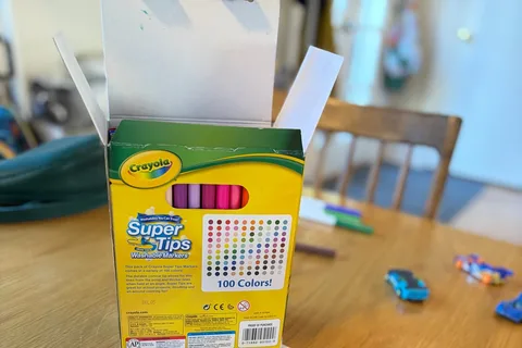 Owner-used Crayola Super Tips 100-count box open on a wooden family art table