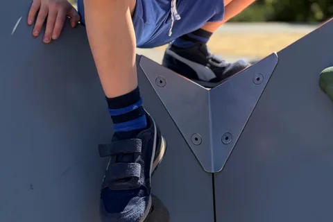 Black PUMA ST Runner Hook and Loop kids' sneakers worn during playground climbing
