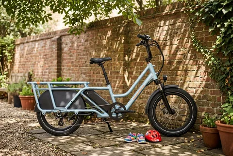 RadWagon 5 cargo e-bike leaning against a brick garden wall with kids shoes and a toy helmet nearby