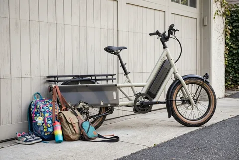 Specialized Globe Haul LT cargo e-bike leaning against a garage door with school bags beside it