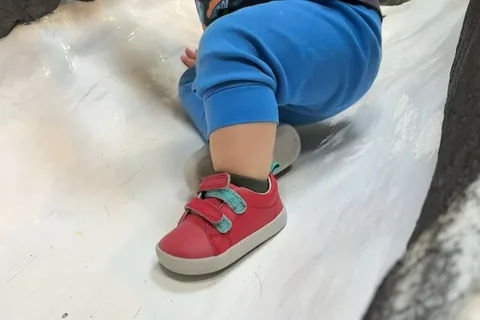 Red Ten Little Everyday Original shoe worn on a playground slide